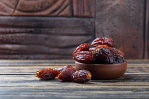 Sweet dates served in a clay bowl on a wooden surface – a natural and energy-boosting healthy food.